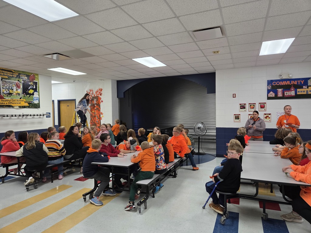 Students hanging orange hands on a kindness tree