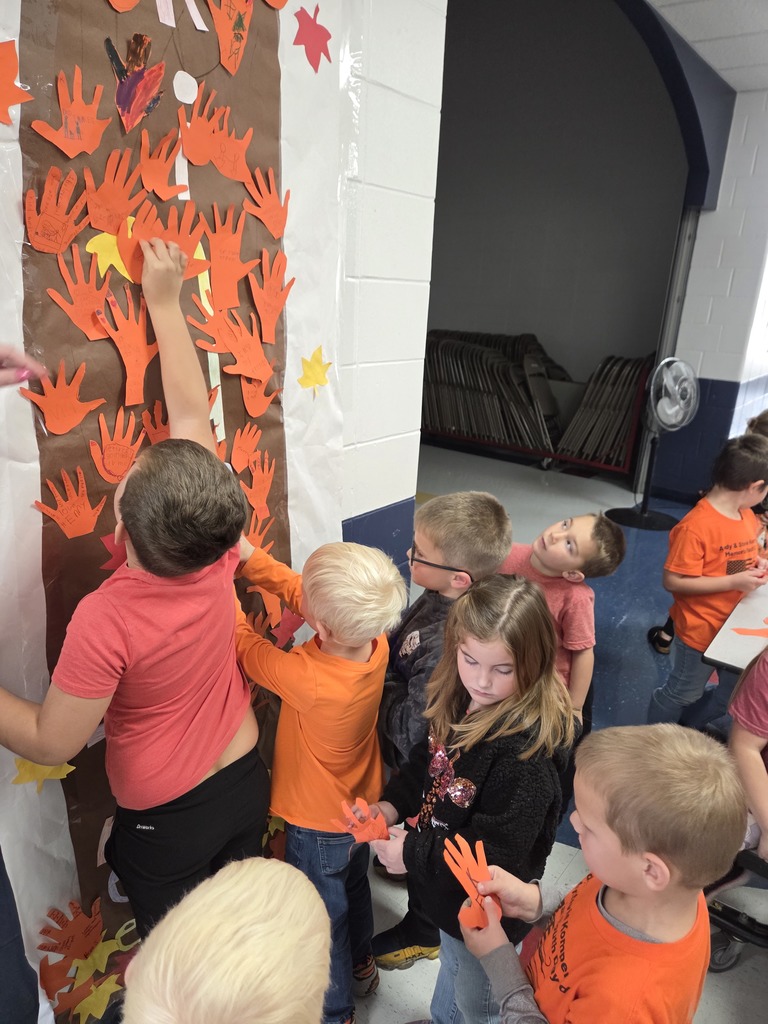 Students hanging orange hands on a kindness tree