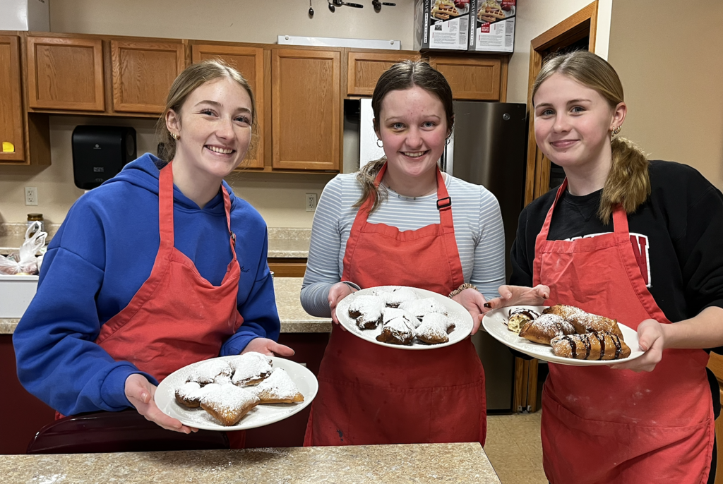 Students with plates of Beignets.  A French-style, deep-fried pastry made from yeast dough.
