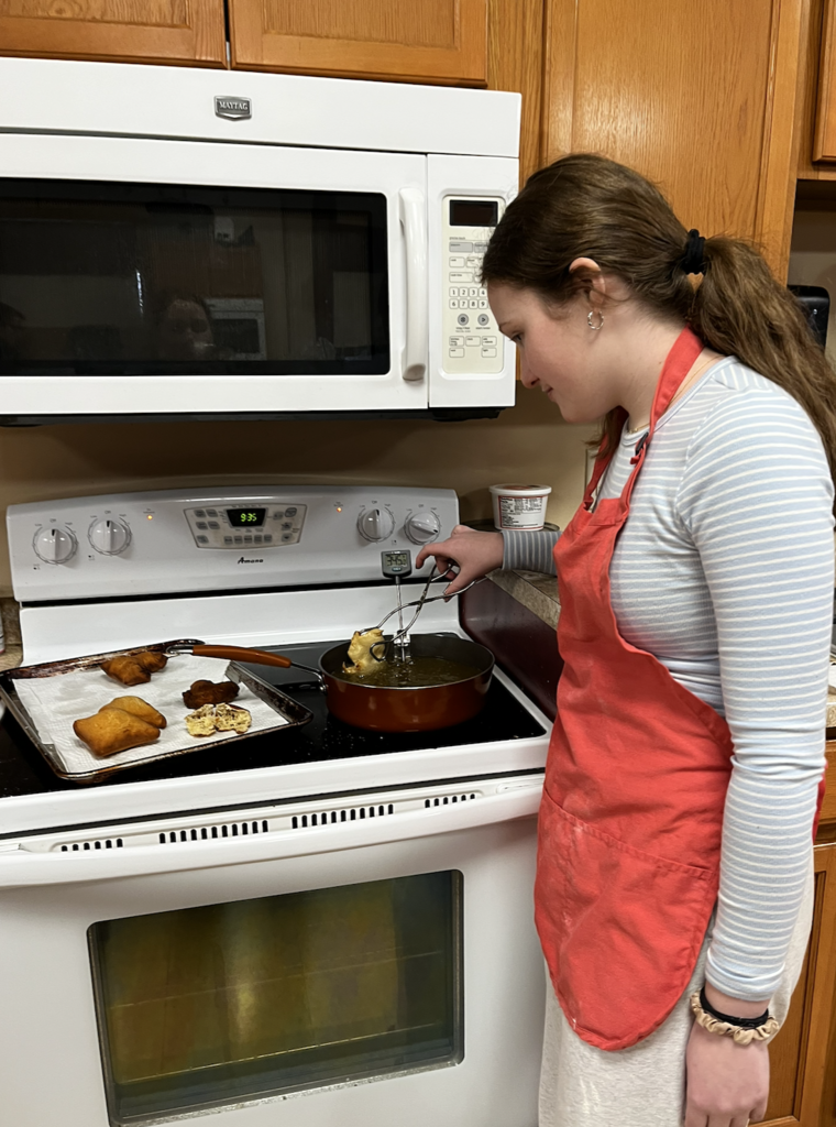 A student deep frying a Beignet. A French-style, deep-fried pastry made from yeast dough