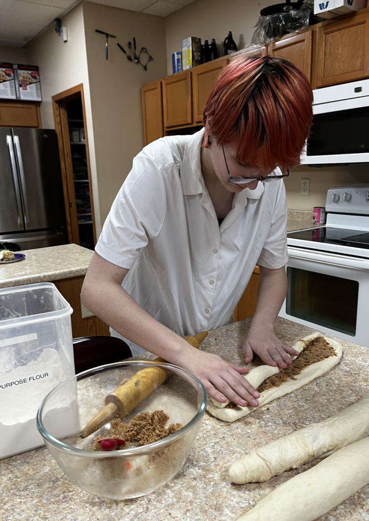 A student rolling the filling into their dough before braiding their king cake.