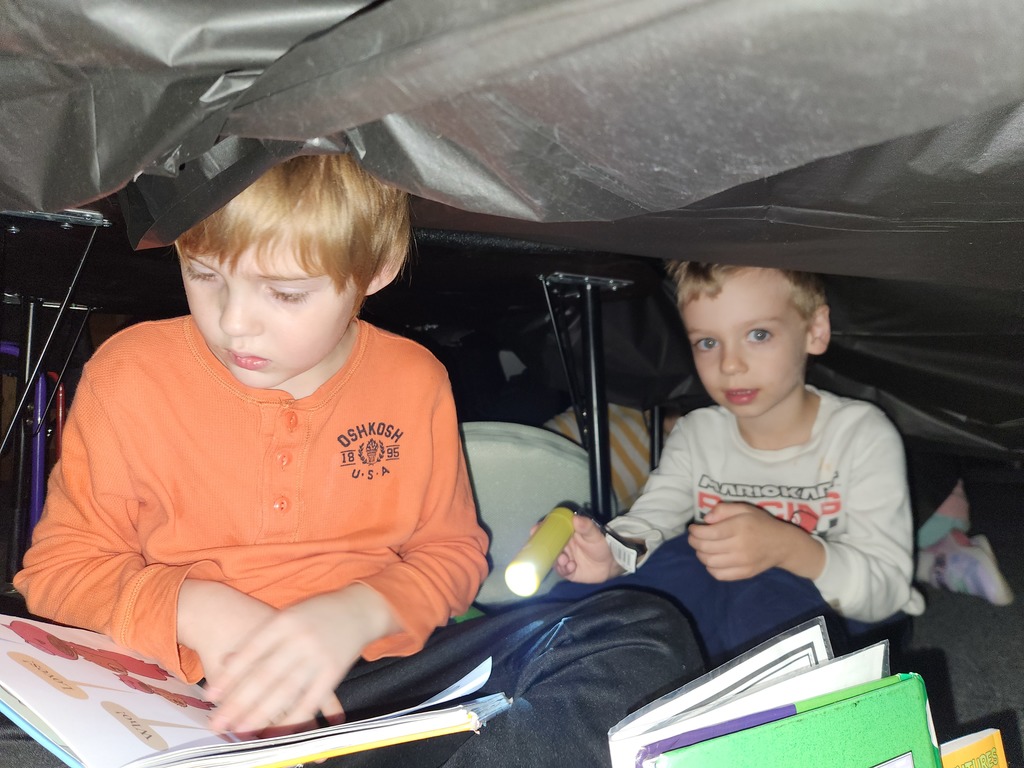Students flashlight reading under forts
