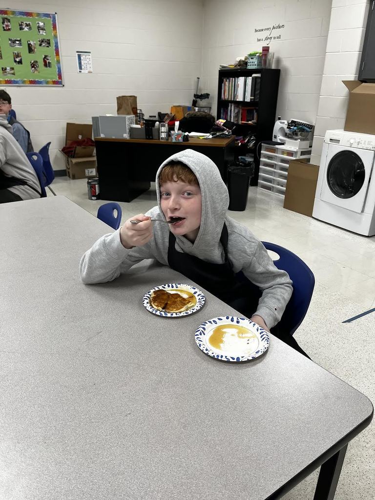 A student takes a big bite of pancake. 
