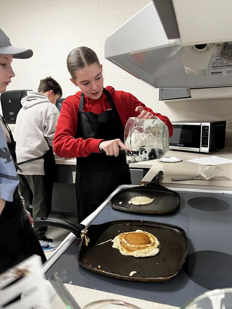 A student pours the last pancake onto the griddle. 