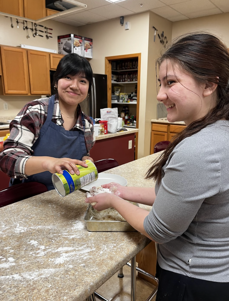 A student applies cornstarch to another student’s hands to reduce stickiness.