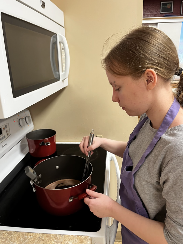 A student stirring their ingredients, waiting for the temperature to reach 250 degrees.
