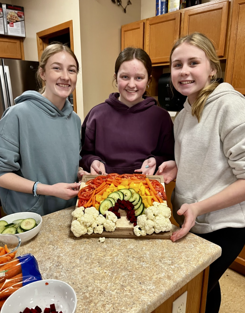 Students displaying their cut vegetable rainbow design.
