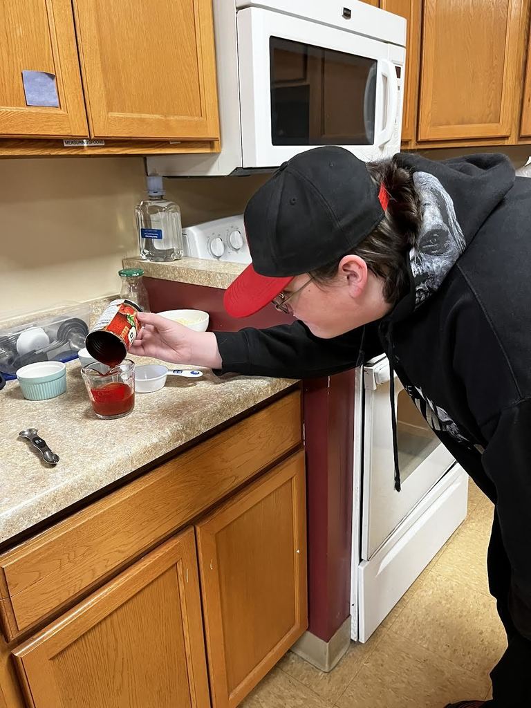 A student accurately measures the amount of sauce needed for a delicious pizza.