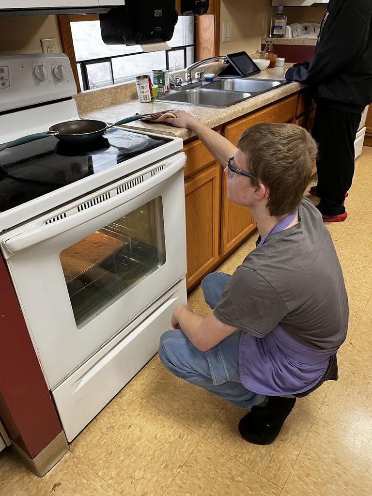 A student checks on their pizza through the oven window.