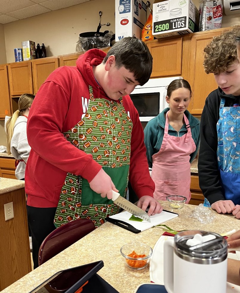 A student cuts vegetables for their ramen.