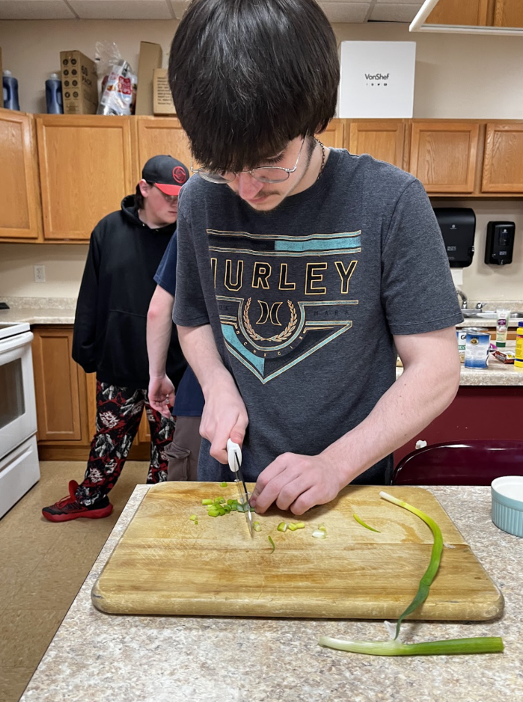 A student cuts vegetables for their ramen.
