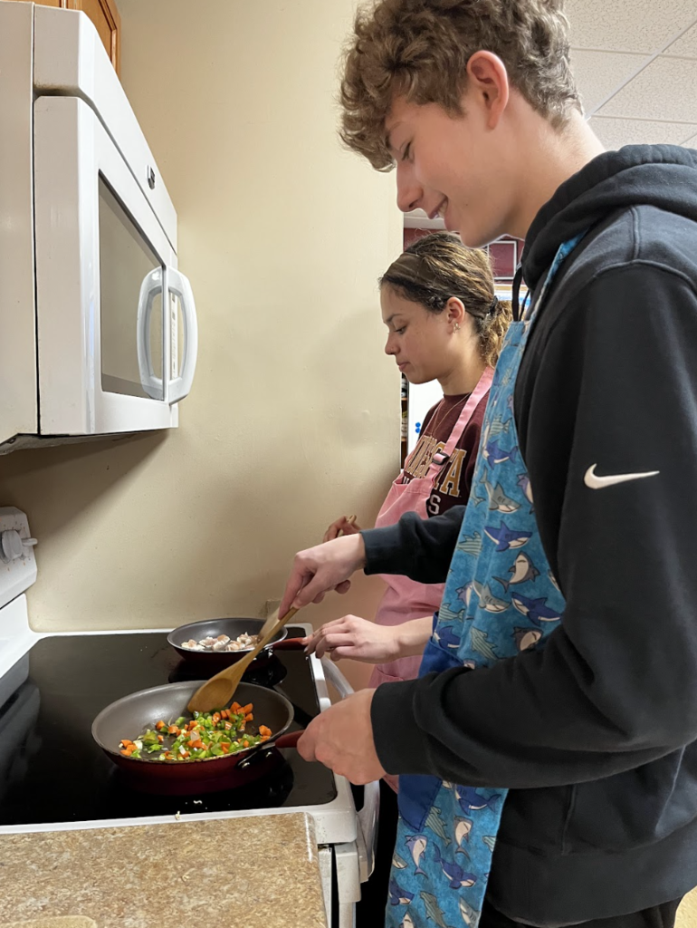 Students cooking their vegetables and protein before assembling their bowls of ramen.