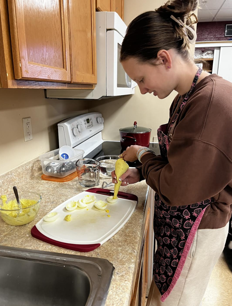 A student fills egg whites to complete their deviled eggs.