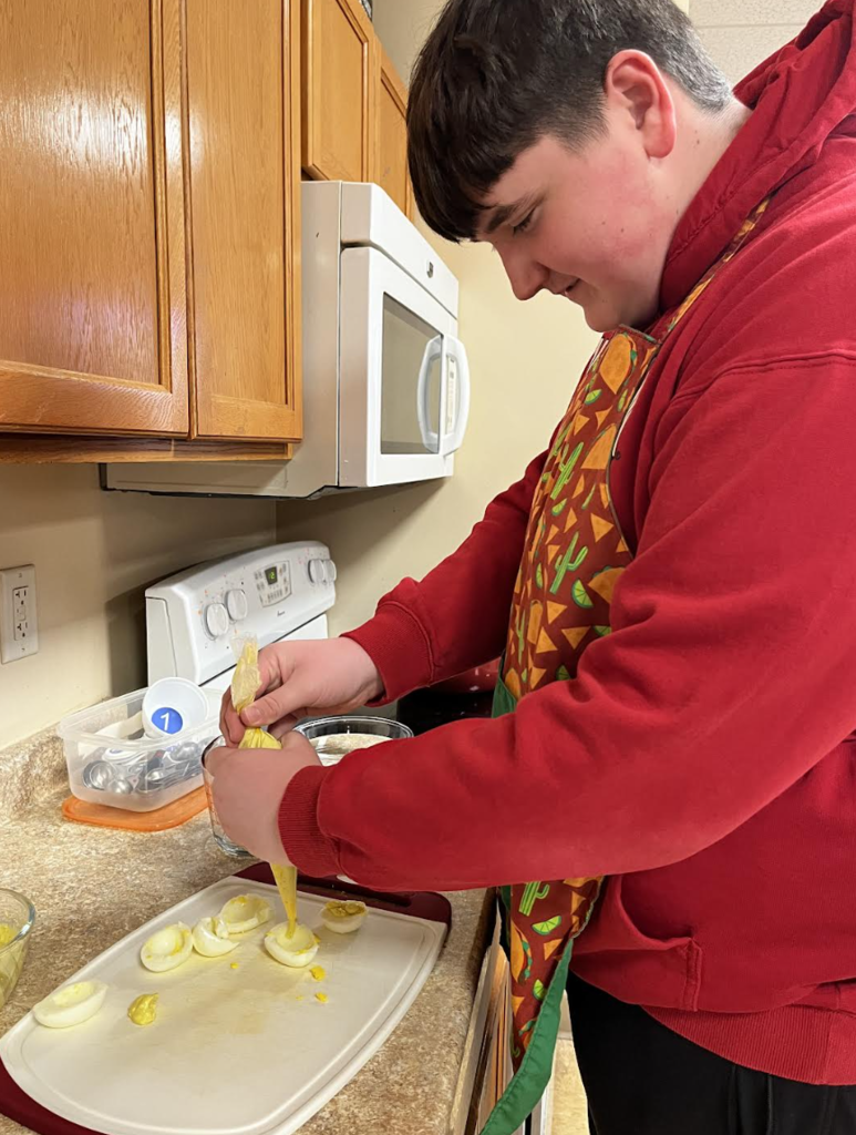 A student fills egg whites to complete their deviled eggs.