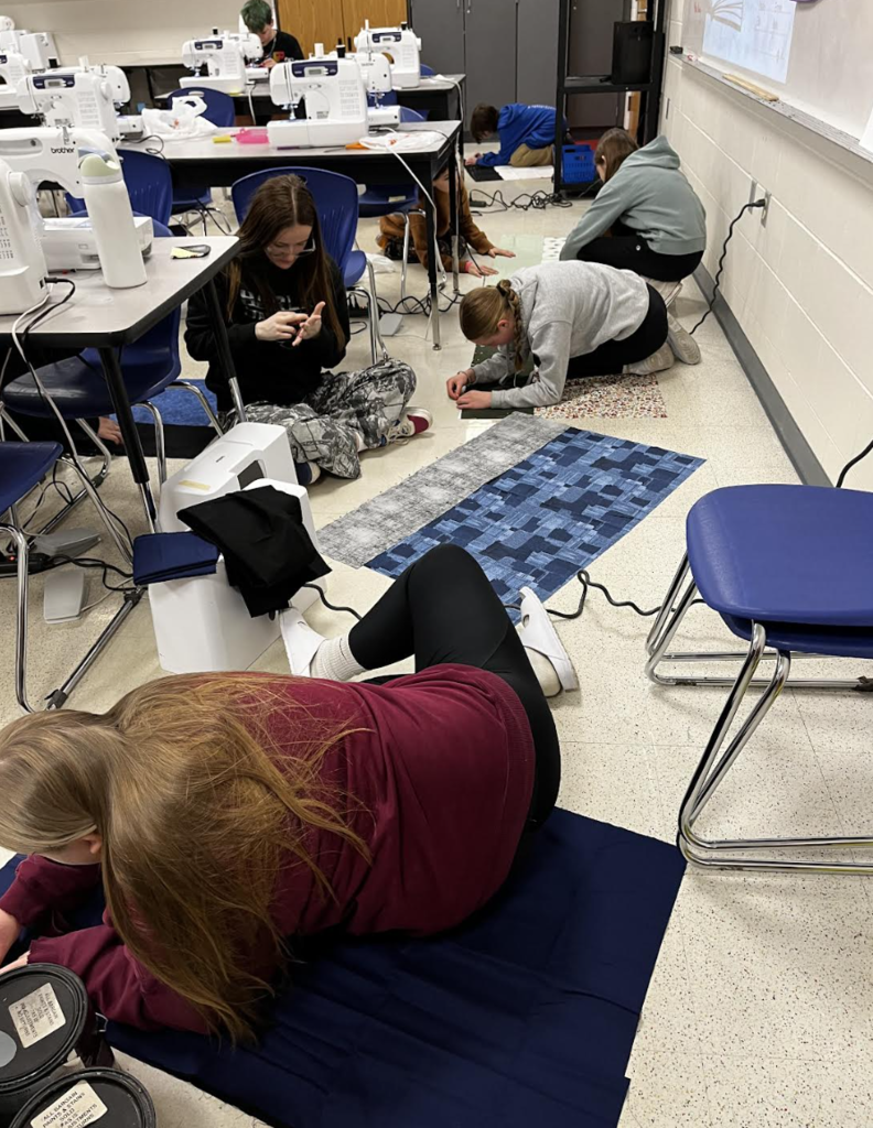 Students work on pinning their pillowcase fabric together. 
