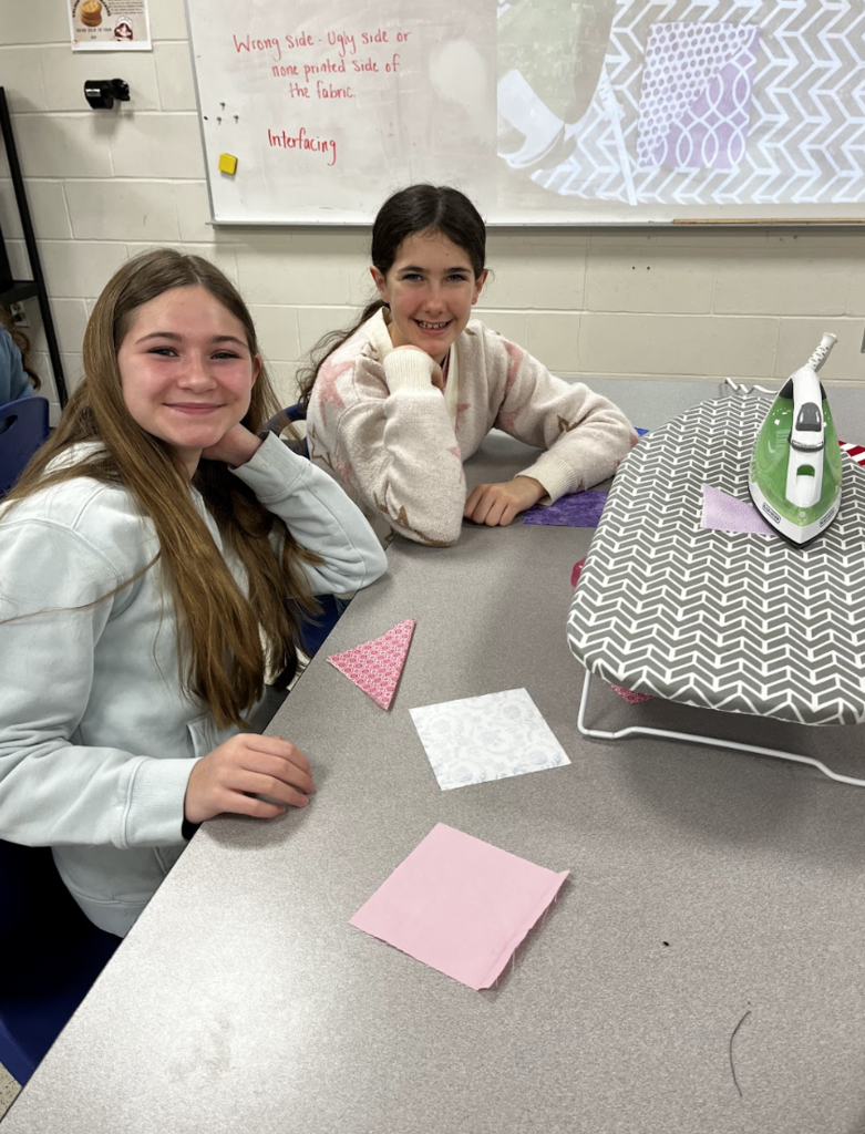 Two students ironing their bookmark fabric.