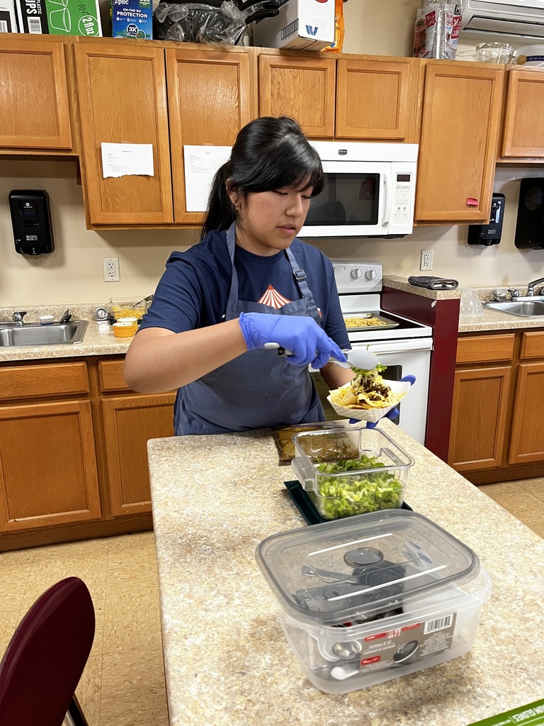 A student preparing nachos for an order.