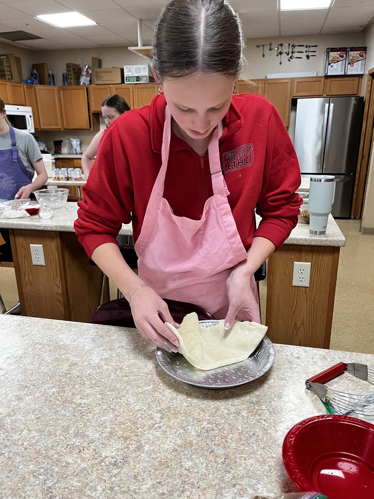 A student places her pie in her pie tin.