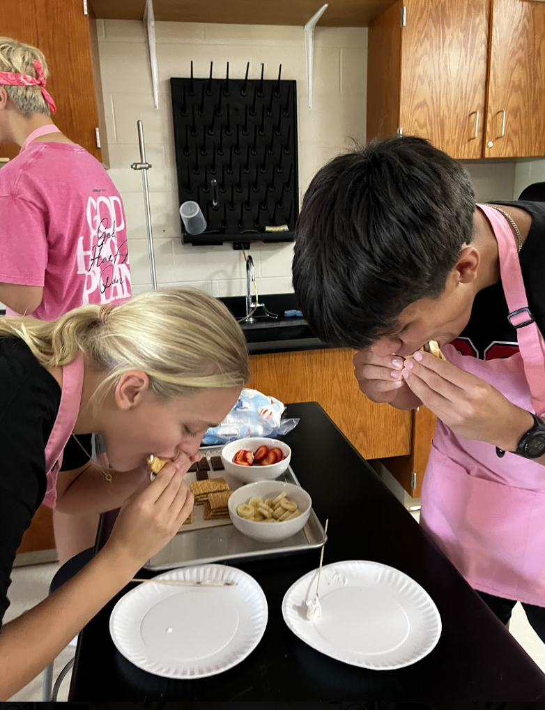 Two students enjoy big bites of their freshly made s’mores.