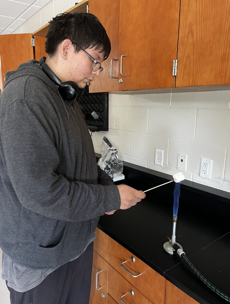 A student carefully roasts their marshmallows over the flame.
