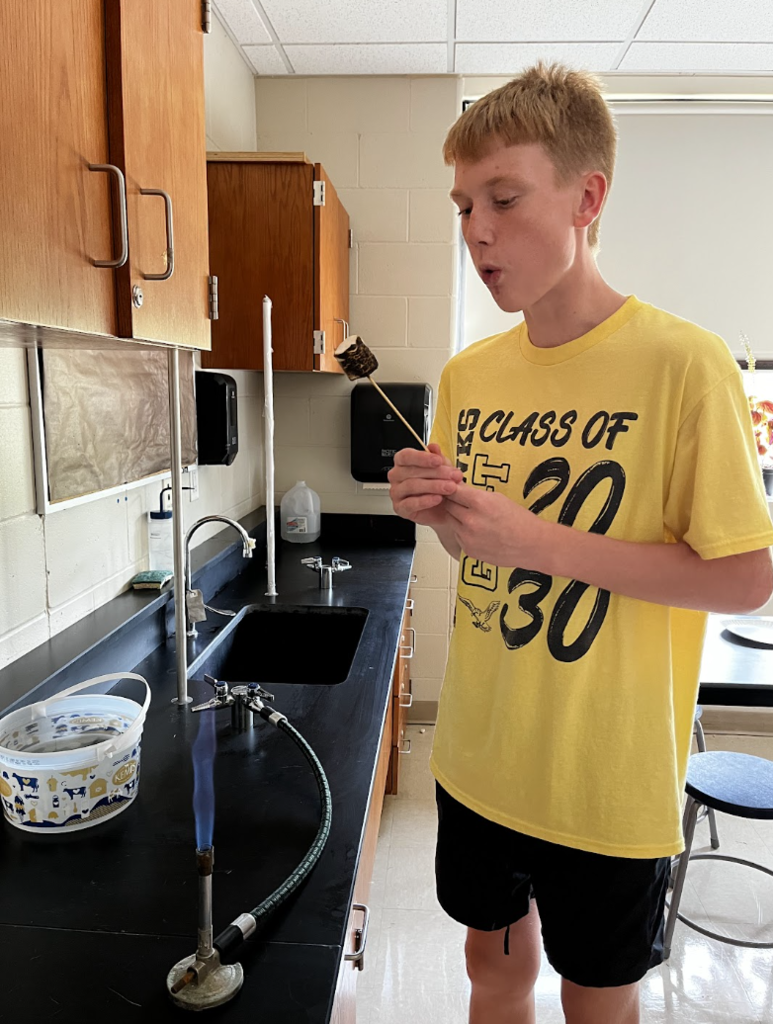A student safely blows out a marshmallow that caught on fire.
