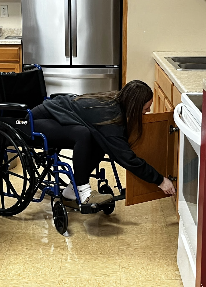 A student attempts to cook while in a wheelchair.
