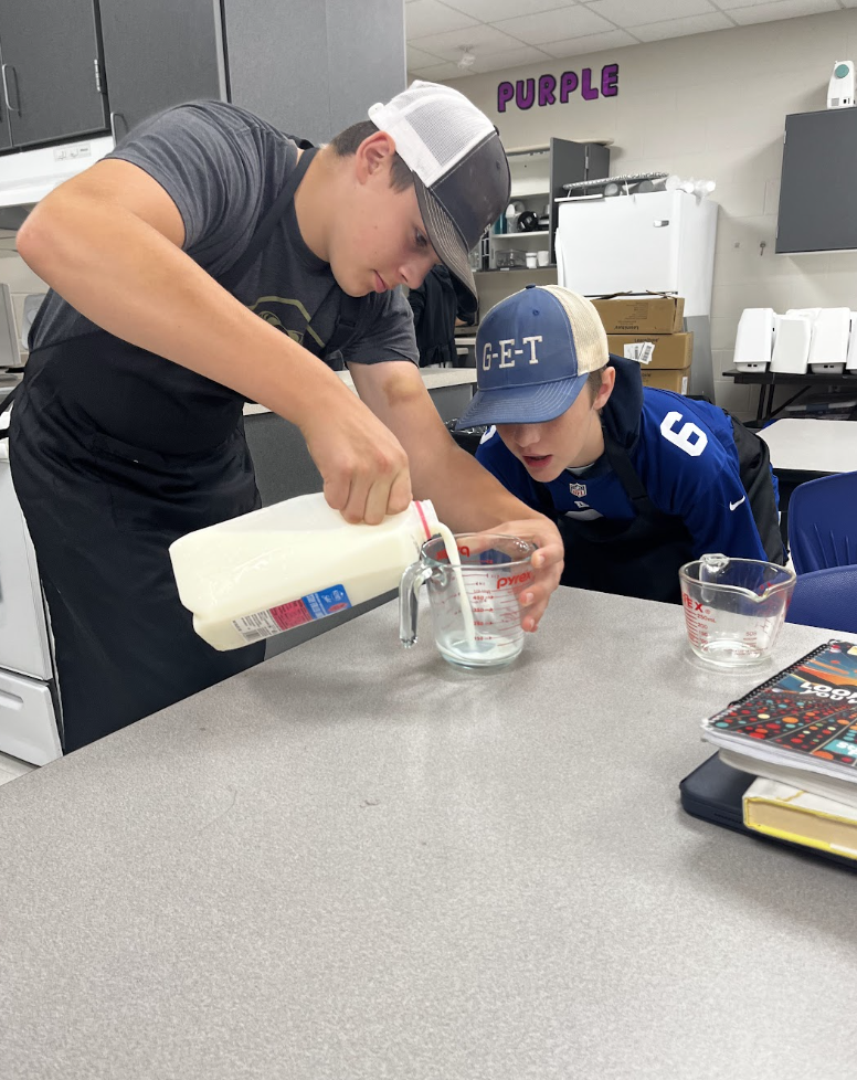 Two students work together to accurately measure the milk. 