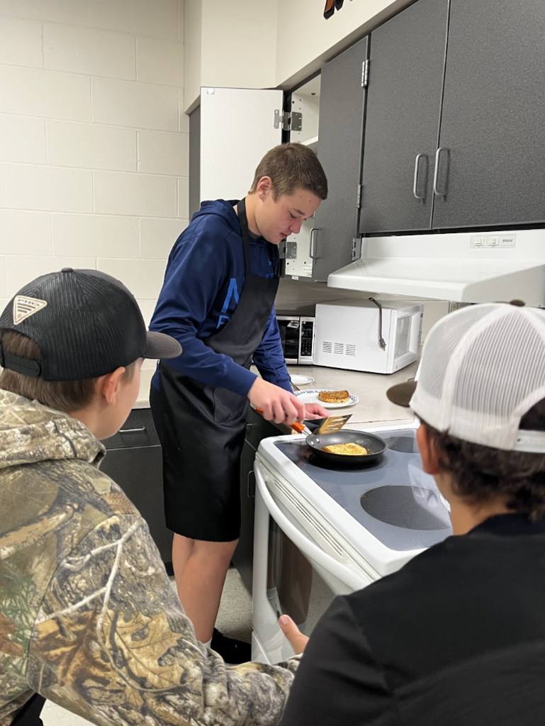 Two students anxiously wait for their partner to flip the French Toast. 