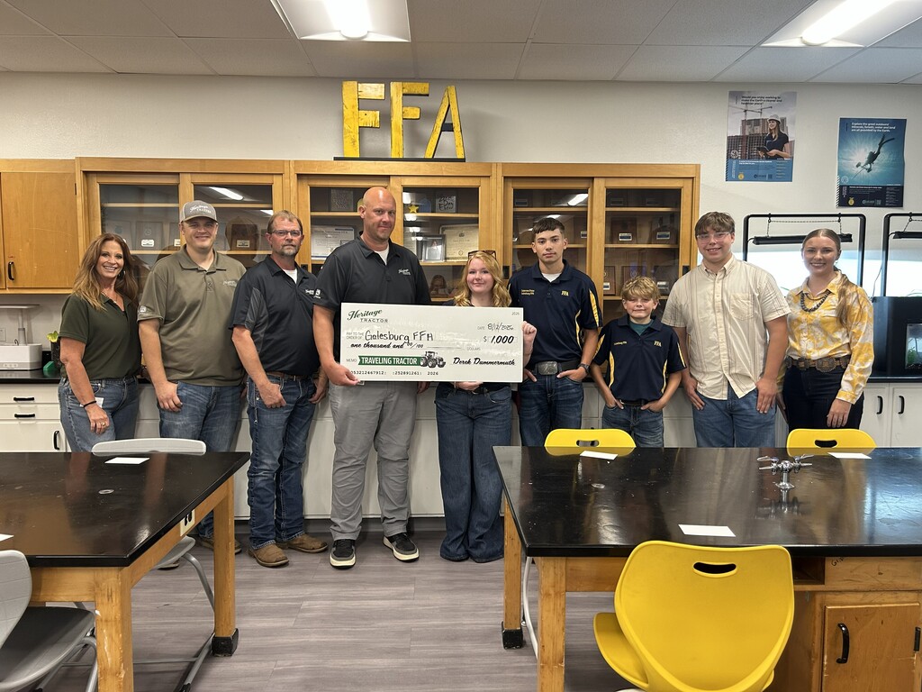 Photo of Heritage Tractor representatives presenting a ceremonial $1,000 donation check to Galesburg FFA. Several people are standing together for a photo, with the donation check displayed prominently in the center. The check represents a community donation through Heritage Tractor’s 2026 Traveling Tractor Tour.