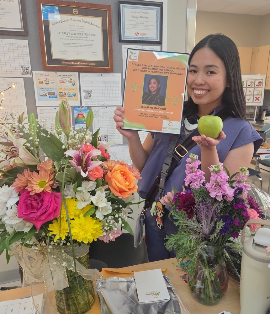 woman holding a green apple and an award with flowers in front of her