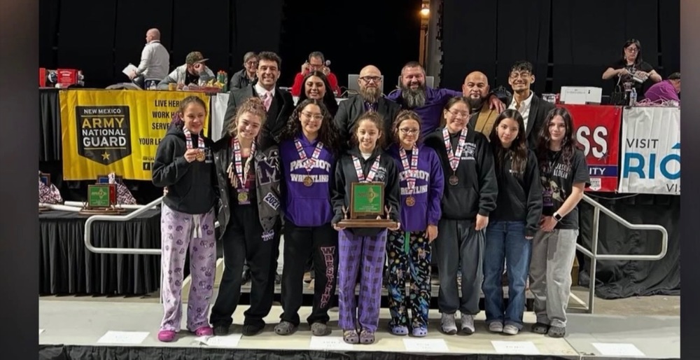 group of students standing in line holding trophies