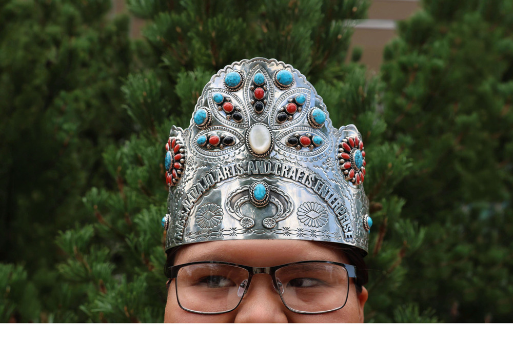 close up of a young girl with glasses wearing a silver crown that says "miss navajo arts and crafts enterprise"
