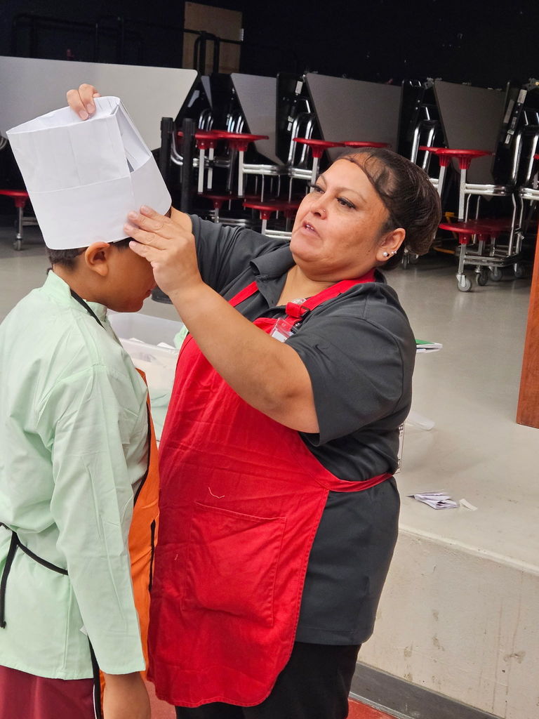SFE worker putting on a chef hat on student