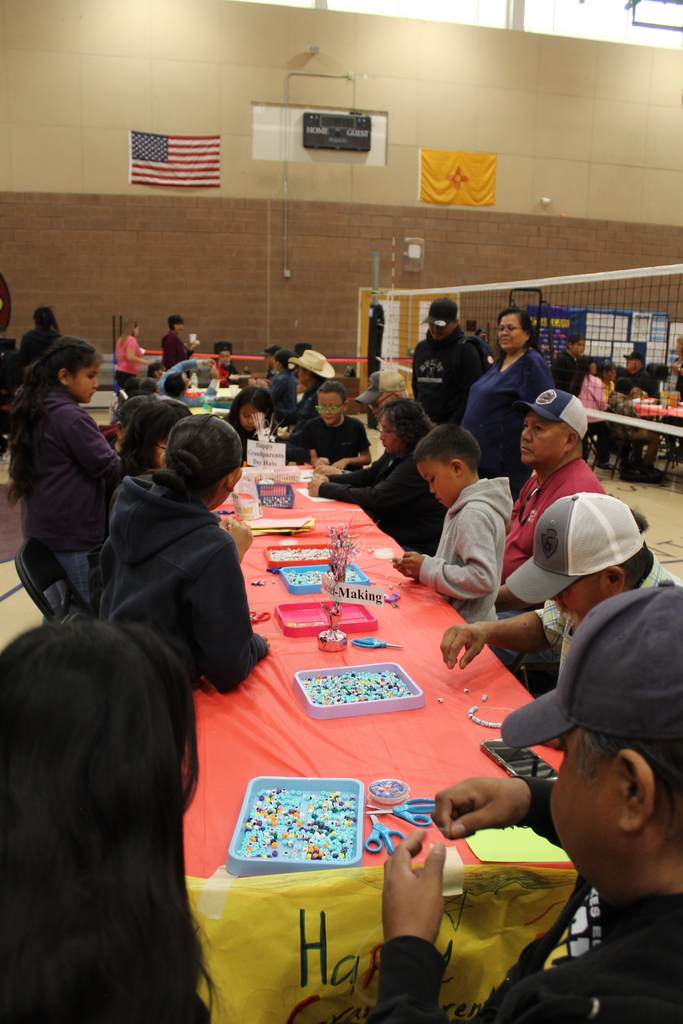 Students and their grandparents sitting at a table working on an activity together.