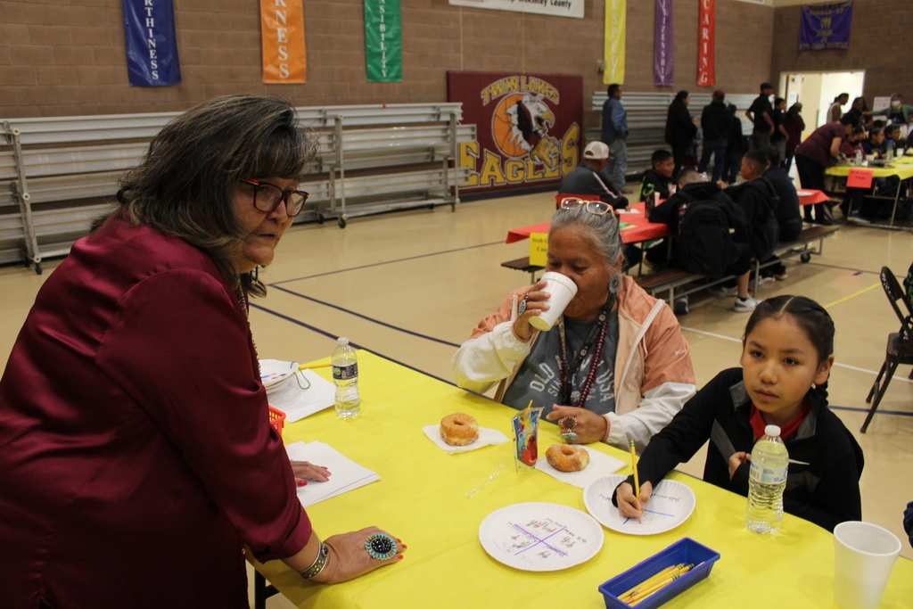 Ms. Dale explaining the grandparents day activity to a student and their grandmother.