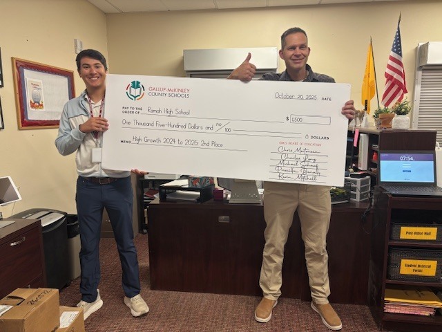 Mr. Quintana and Mr. Gibbons holding the large check from the school district.