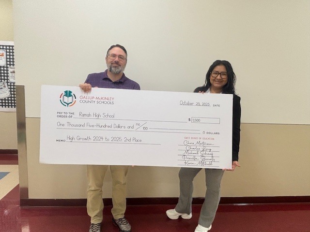 Mr. and Mrs. Morris holding the large check from the school district.