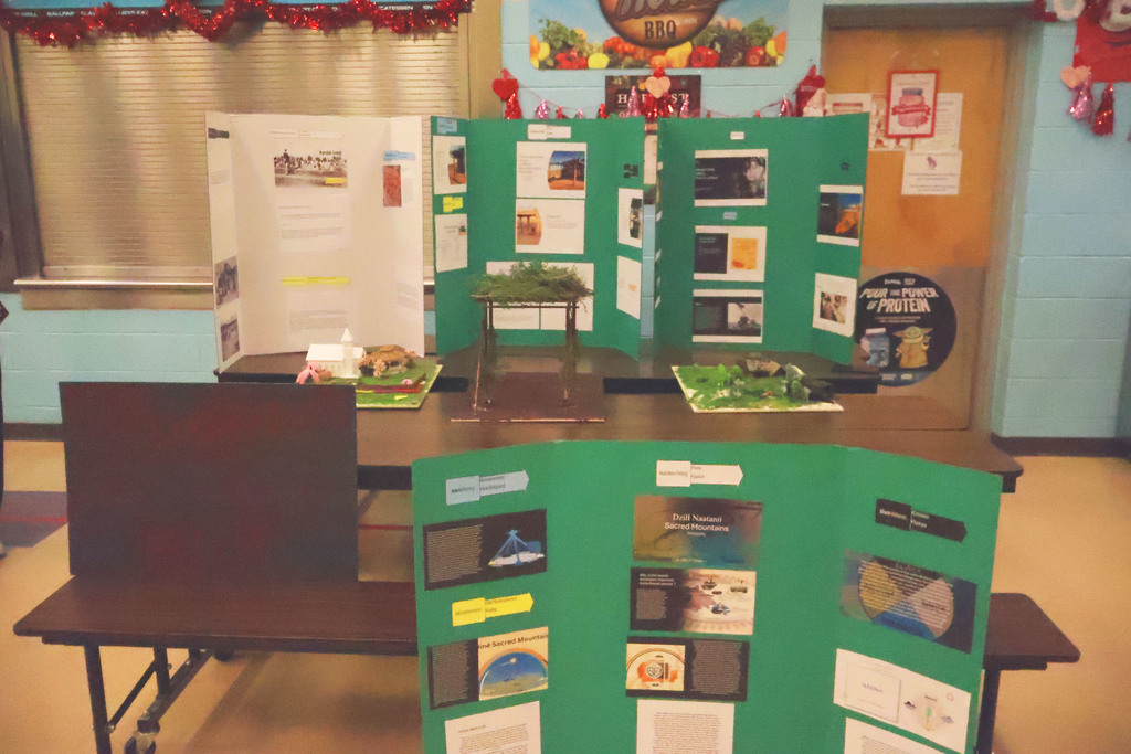One white and three green posterboards of school student presentation in a cafeteria 