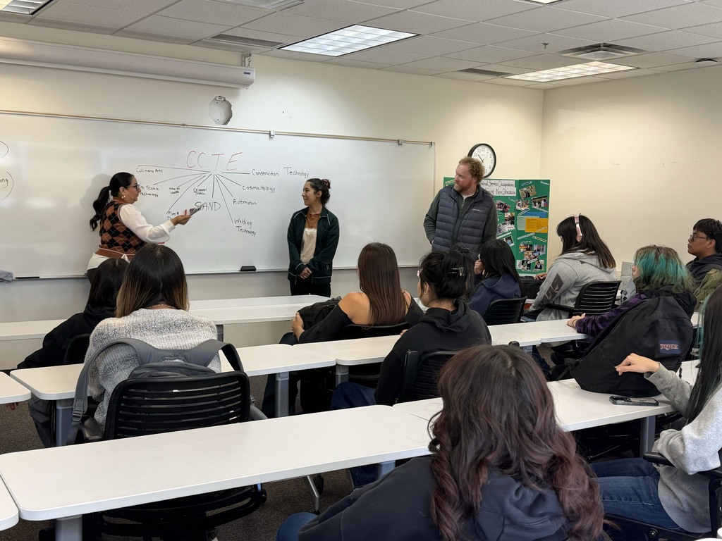 three instructors observe a dry erase board while students onlook