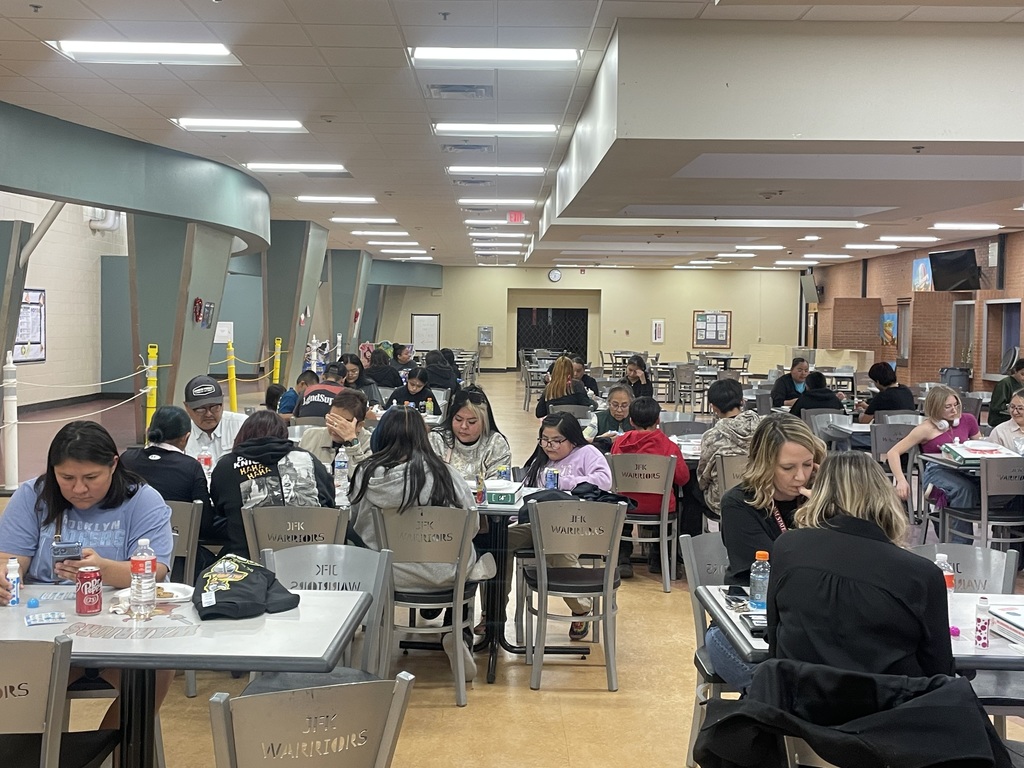 Families sit in an open area with bingo cards and pizza on tables