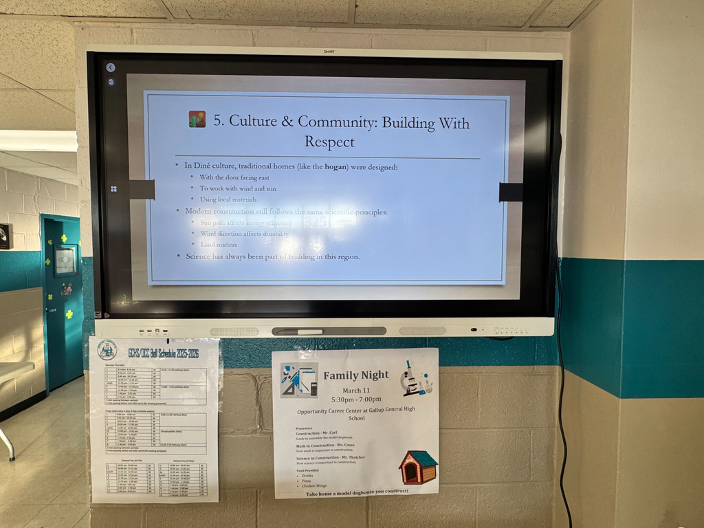 Monitor on wall shows screen with title "Culture & Community: Building With Respect". Two posters below, one titled "Family Night" with a dog.