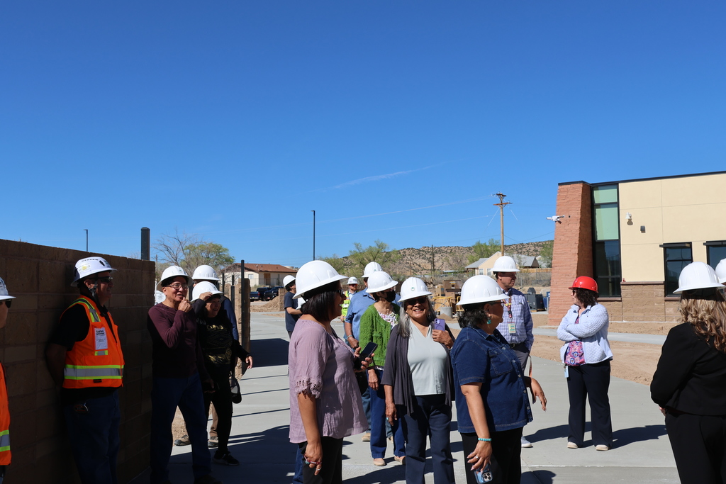 People in hard hats standing in front of a building under construction.