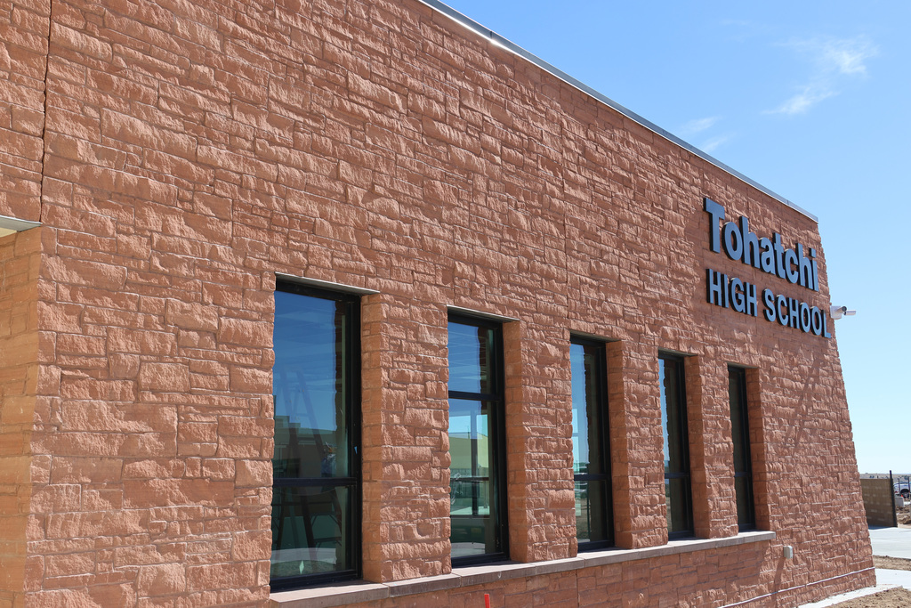 Building with a brick wall and large windows. The name "Tonatchi High School" is on the wall.