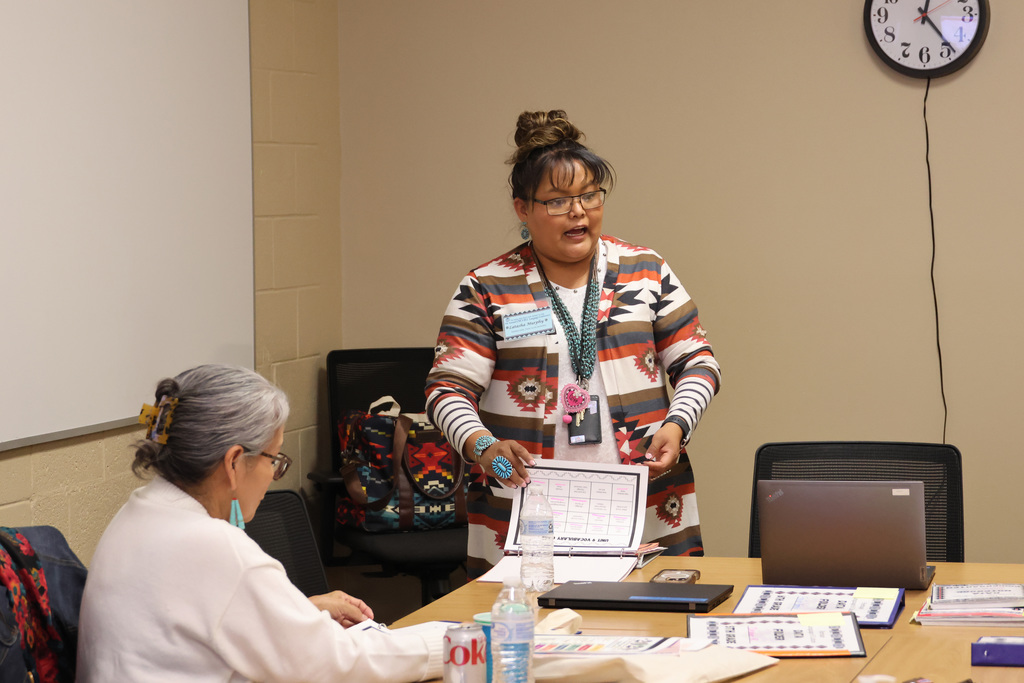 A women presents in front of others. She is wearing native jewelry.