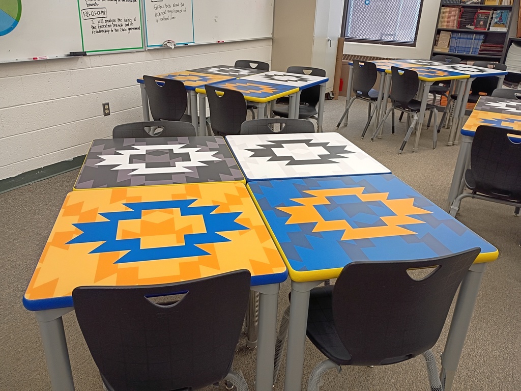 students desk , classroom, gray carpet. yellow, blue, black, and white desks