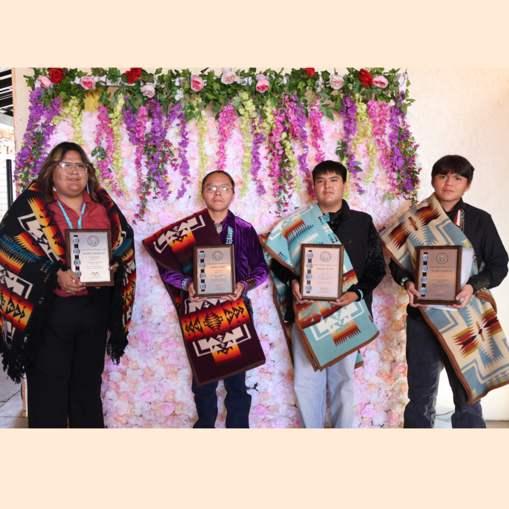 one female, three male students holding award plaques for Navajo Seal of Bilingual Proficiency, all holding plaque in front of them, pendelton blankets are around the students