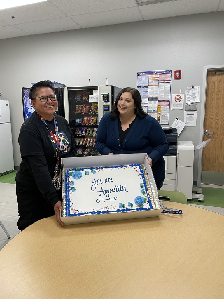Staff members displaying a cake for staff appreciation week.