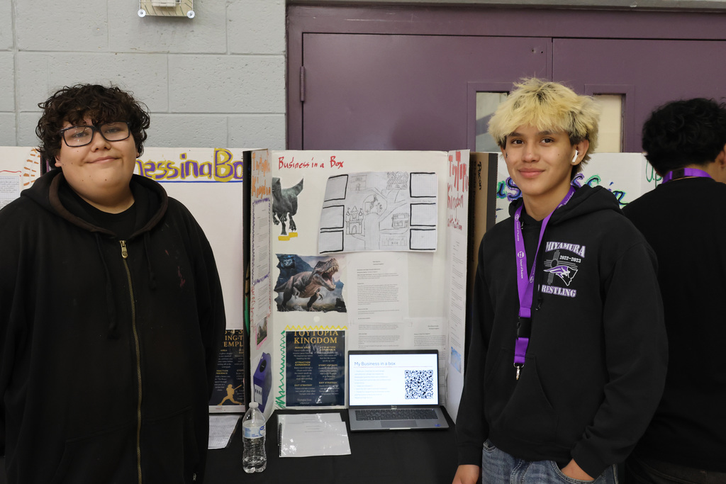 two students smile in front of presentation