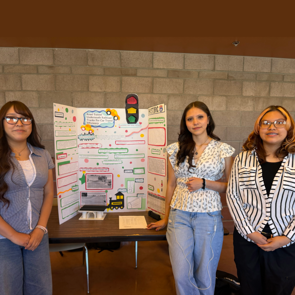 Three women in front of a poster with drawings and a traffic light on a table.