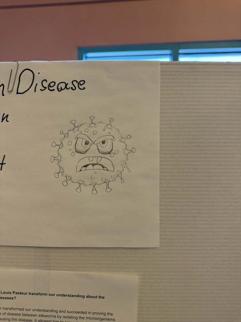 A whiteboard with a drawing of a virus, labeled "Virus Disease," attached to a wall.